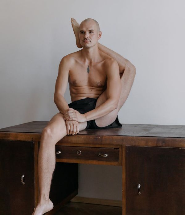 Man performing a controlled strength exercise in a minimalist, bright studio.
